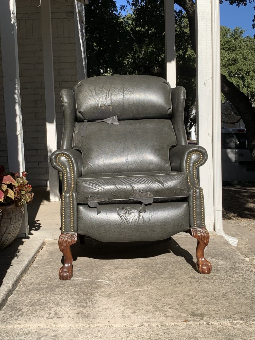Heavily damaged gray leather recliner before restoration